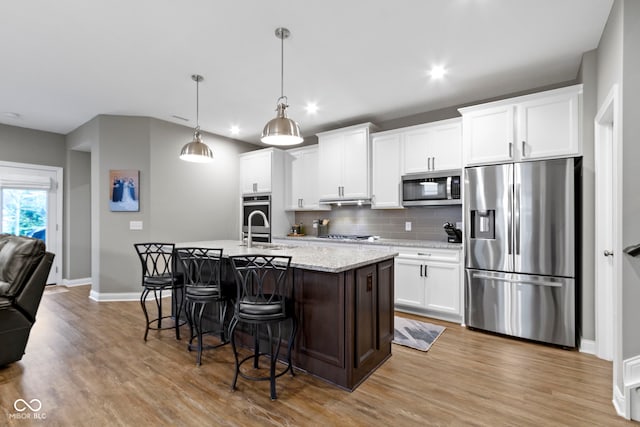 kitchen with white cabinetry, an island with sink, hanging light fixtures, and appliances with stainless steel finishes