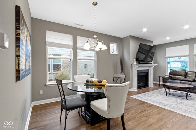 dining space featuring a fireplace, dark wood-type flooring, and a notable chandelier