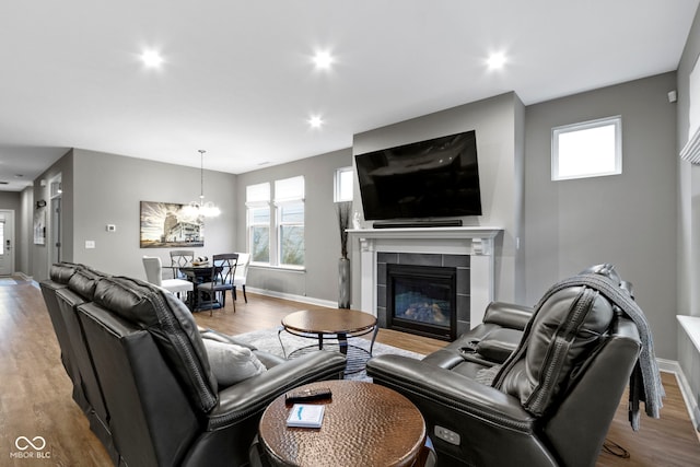 living room featuring a notable chandelier, light wood-type flooring, and a tile fireplace