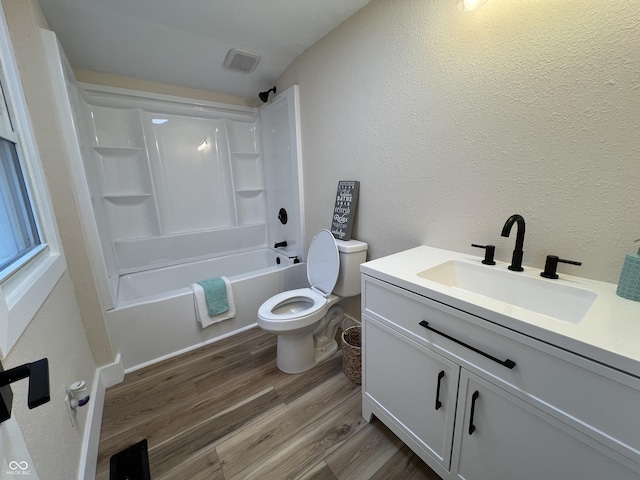 full bathroom with toilet, hardwood / wood-style floors, vanity, and washtub / shower combination