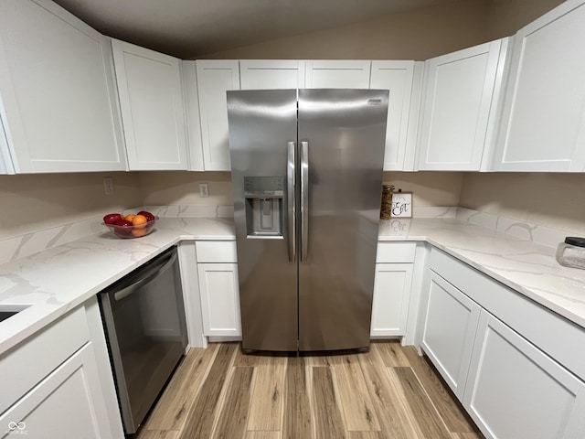 kitchen with light stone countertops, white cabinets, stainless steel appliances, and light hardwood / wood-style floors