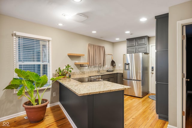 kitchen with sink, stainless steel refrigerator with ice dispenser, kitchen peninsula, gray cabinets, and black electric stovetop