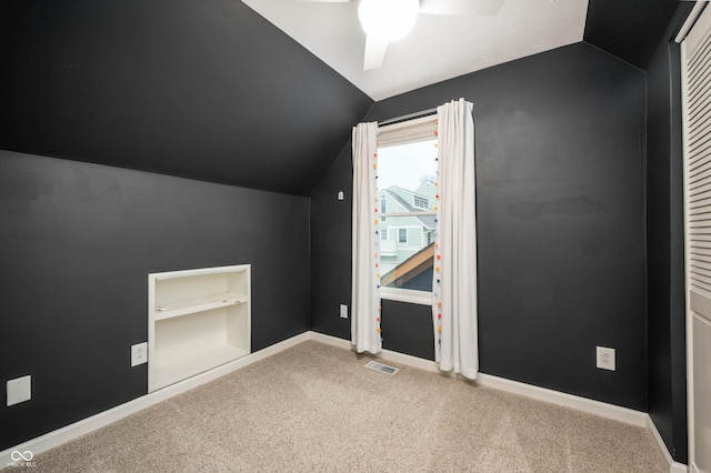 additional living space with built in shelves, light colored carpet, ceiling fan, and lofted ceiling