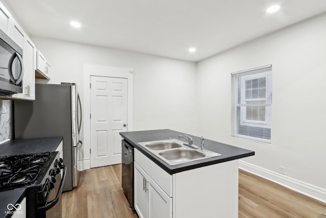 kitchen with white cabinets, sink, stainless steel appliances, and an island with sink