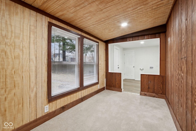 spare room featuring lofted ceiling, light colored carpet, wooden walls, and wood ceiling