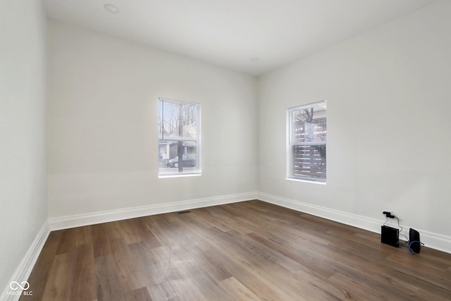 unfurnished room with baseboards and dark wood-style flooring