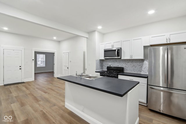 kitchen with backsplash, appliances with stainless steel finishes, a sink, and dark countertops