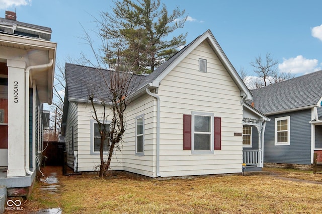 rear view of property featuring a yard and a shingled roof