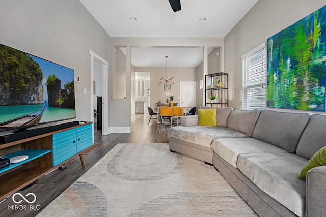 living room featuring ceiling fan with notable chandelier and wood-type flooring