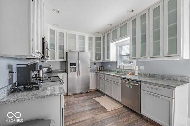 kitchen featuring white cabinets, sink, light stone countertops, appliances with stainless steel finishes, and dark hardwood / wood-style flooring