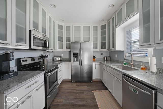 kitchen with white cabinets, sink, light stone countertops, appliances with stainless steel finishes, and dark hardwood / wood-style flooring