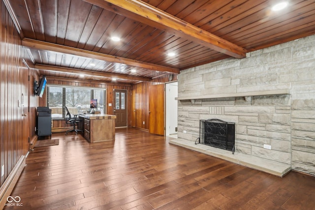 unfurnished office featuring a stone fireplace, wooden walls, beamed ceiling, and dark wood-type flooring