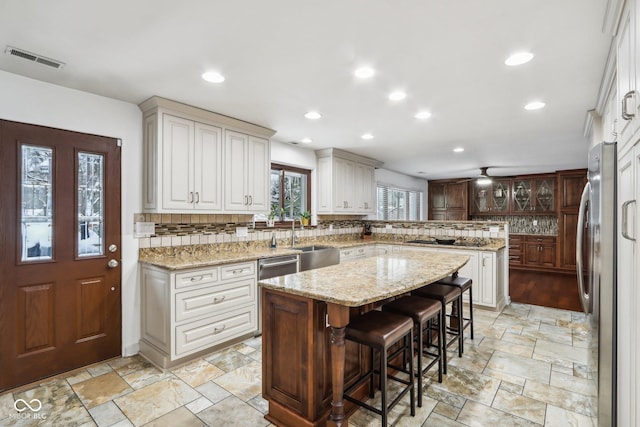 kitchen featuring sink, a kitchen breakfast bar, tasteful backsplash, a kitchen island, and appliances with stainless steel finishes