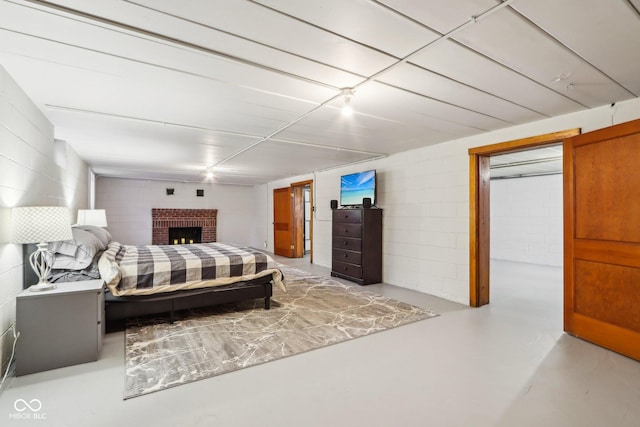 bedroom with concrete flooring and a brick fireplace