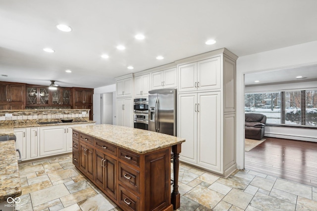 kitchen featuring a center island, white cabinets, light stone countertops, a baseboard radiator, and stainless steel appliances