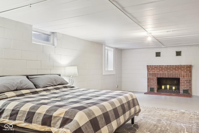 bedroom featuring multiple windows, a fireplace, and concrete flooring