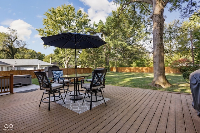 deck with a hot tub and a lawn