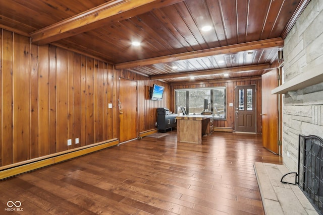 unfurnished office with a fireplace, a baseboard heating unit, dark wood-type flooring, and wooden walls