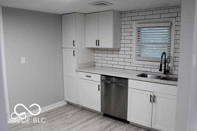 kitchen with sink, stainless steel dishwasher, decorative backsplash, light hardwood / wood-style floors, and white cabinetry