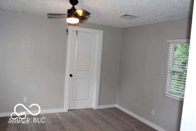 empty room with carpet flooring, ceiling fan, and a textured ceiling