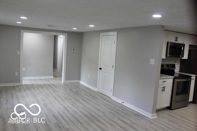 kitchen with tasteful backsplash, white cabinetry, light hardwood / wood-style floors, and electric range oven