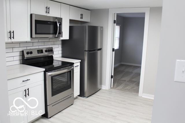 kitchen with light carpet, appliances with stainless steel finishes, backsplash, and white cabinetry