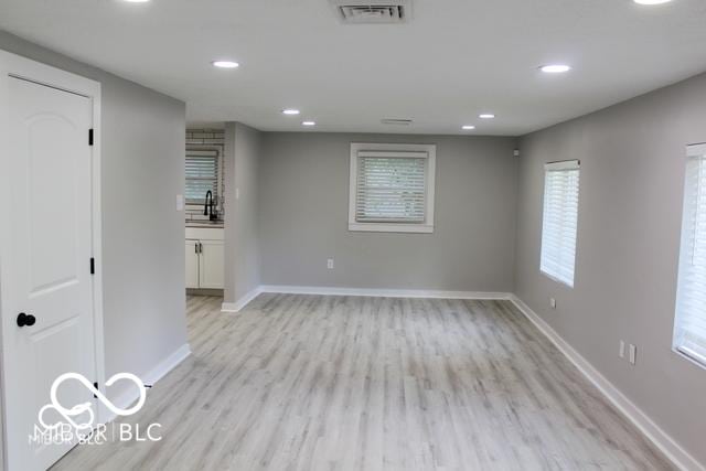 empty room with a wealth of natural light, sink, and light hardwood / wood-style floors