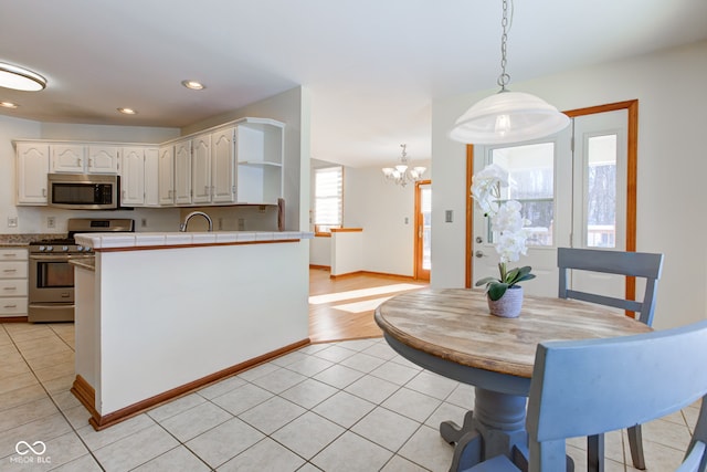 kitchen featuring pendant lighting, sink, an inviting chandelier, white cabinetry, and appliances with stainless steel finishes