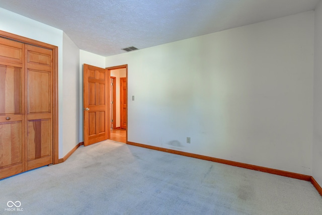 unfurnished bedroom featuring light carpet and a textured ceiling