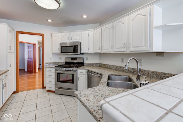 kitchen featuring light tile patterned floors, sink, stainless steel appliances, and white cabinetry