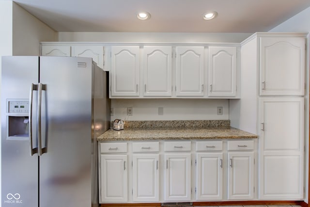 kitchen with white cabinets, stainless steel refrigerator with ice dispenser, and light stone countertops