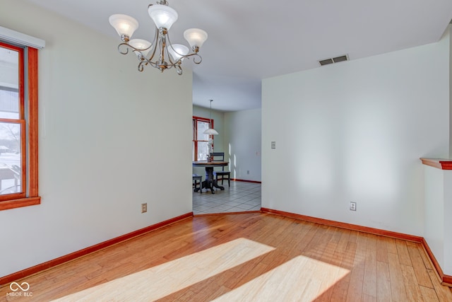 unfurnished room with a chandelier and light hardwood / wood-style flooring