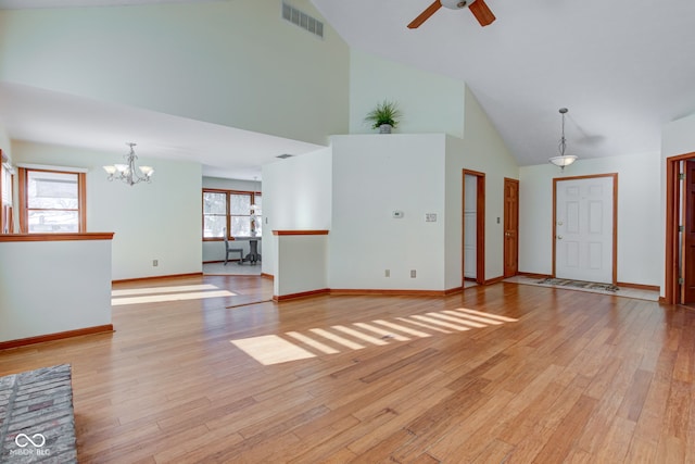 unfurnished living room with high vaulted ceiling, ceiling fan with notable chandelier, and light hardwood / wood-style flooring