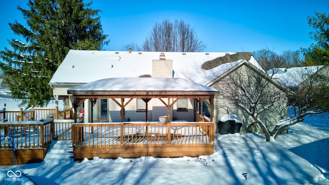 snow covered back of property with a wooden deck