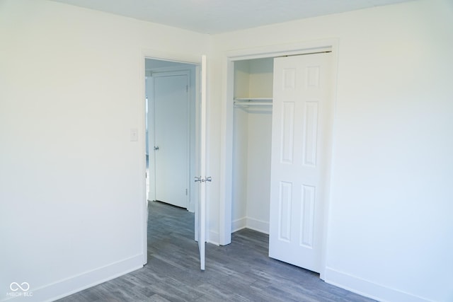 unfurnished bedroom with dark hardwood / wood-style flooring and a closet