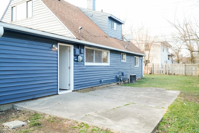 rear view of property with a lawn, a patio area, and central AC unit