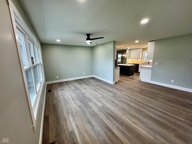 unfurnished living room featuring ceiling fan, hardwood / wood-style floors, a textured ceiling, and sink