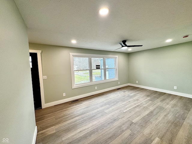 spare room with a textured ceiling, light hardwood / wood-style flooring, and ceiling fan