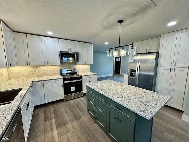 kitchen featuring a kitchen island, white cabinetry, backsplash, and appliances with stainless steel finishes