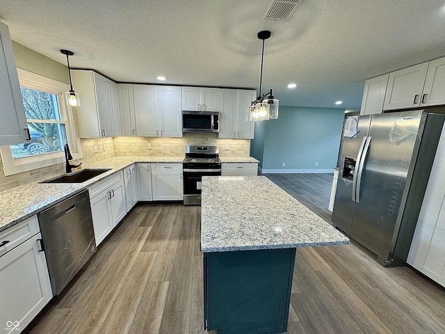 kitchen featuring pendant lighting, sink, white cabinetry, and stainless steel appliances