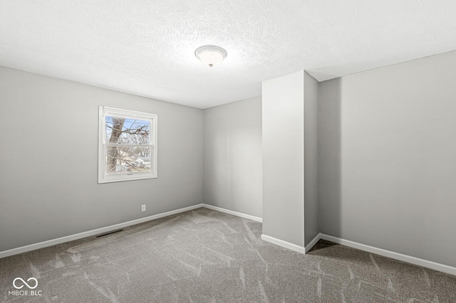 carpeted empty room featuring a textured ceiling