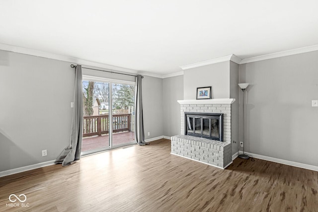 unfurnished living room with wood-type flooring, a brick fireplace, and ornamental molding