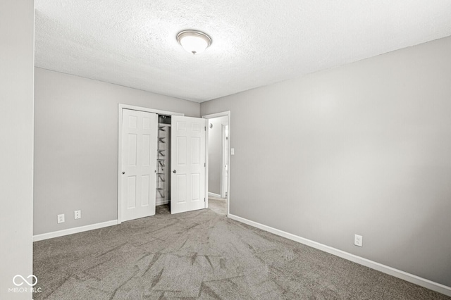 unfurnished bedroom featuring a textured ceiling, carpet floors, and a closet