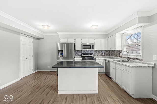 kitchen with tasteful backsplash, stainless steel appliances, sink, white cabinets, and a center island