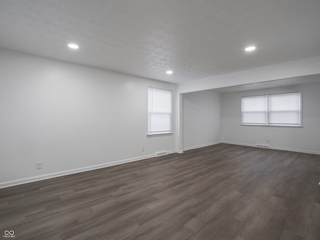 unfurnished room with a textured ceiling and dark hardwood / wood-style floors