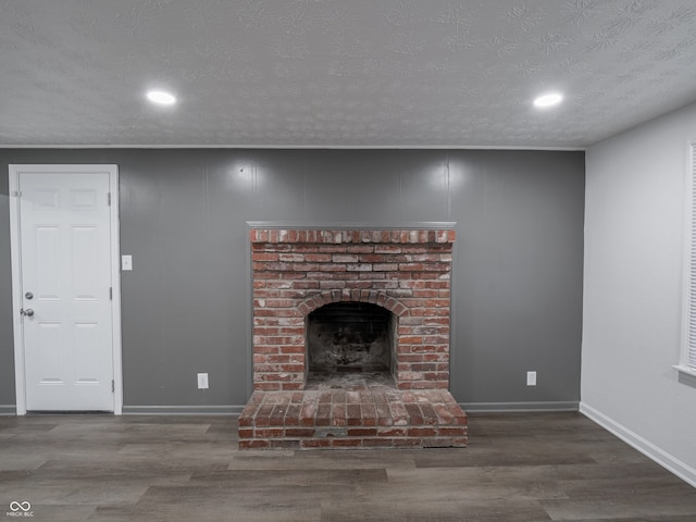 unfurnished living room with hardwood / wood-style floors, a fireplace, and a textured ceiling