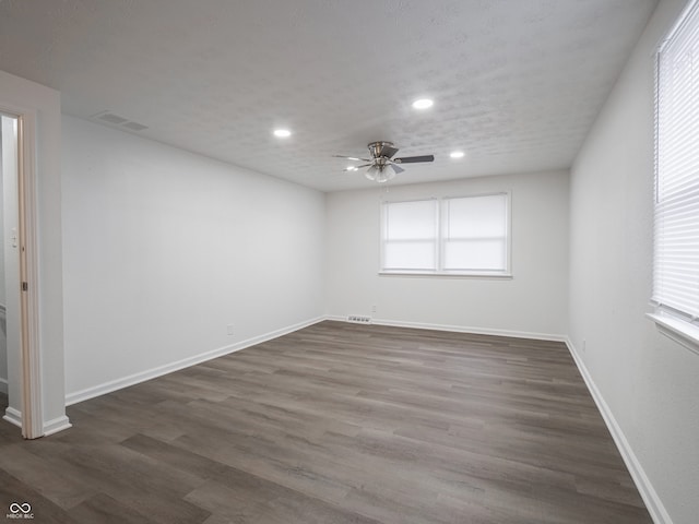 spare room with plenty of natural light, dark wood-type flooring, and ceiling fan