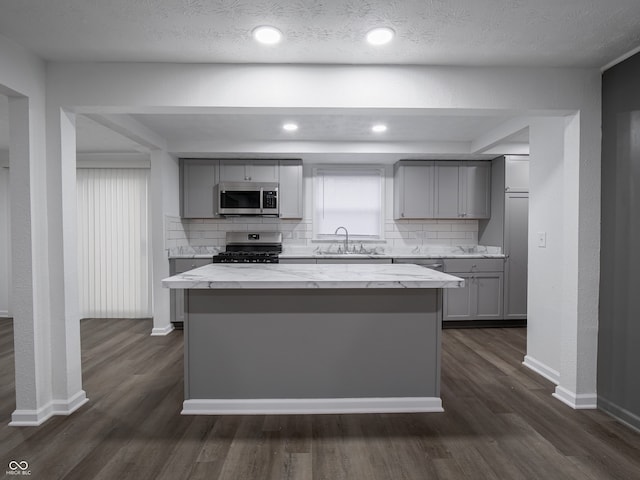 kitchen with gray cabinets, decorative backsplash, a center island, and appliances with stainless steel finishes