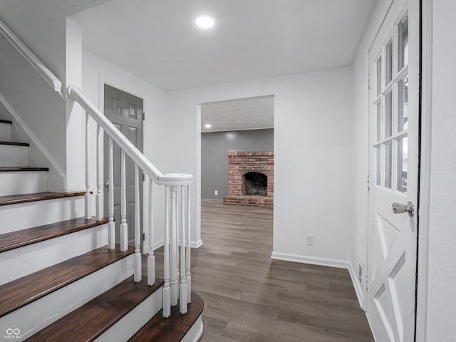 entrance foyer featuring dark wood-type flooring and a brick fireplace