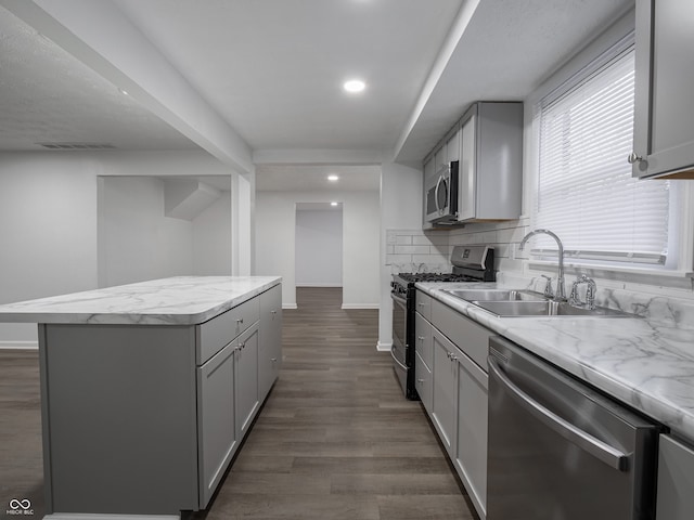 kitchen featuring tasteful backsplash, stainless steel appliances, sink, a center island, and gray cabinets